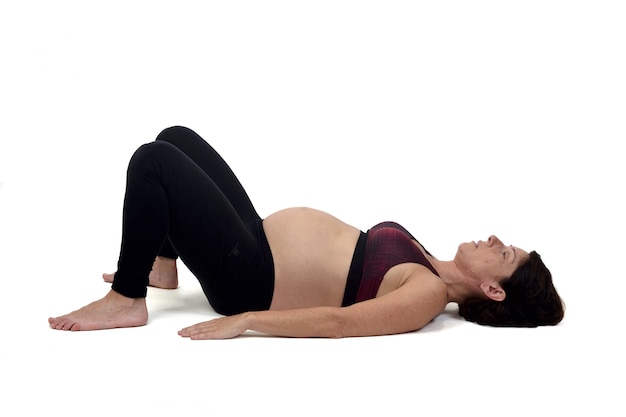 Femme enceinte faisant des exercices au sol sur fond blanc,