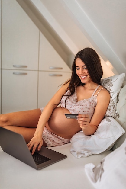 Femme enceinte faisant ses courses en ligne depuis son lit