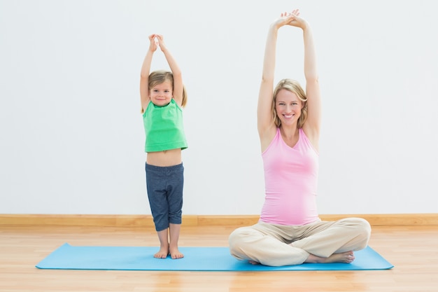 Femme enceinte et fille, faire du yoga ensemble