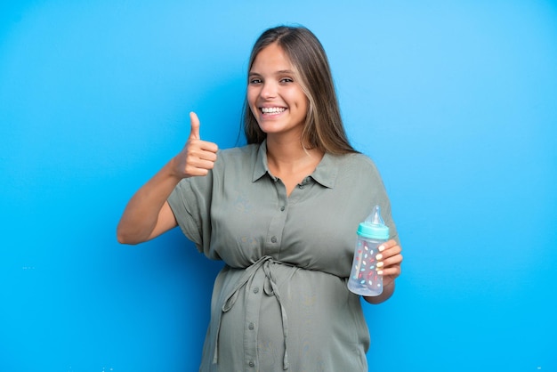 Femme enceinte sur fond bleu donnant un coup de pouce geste