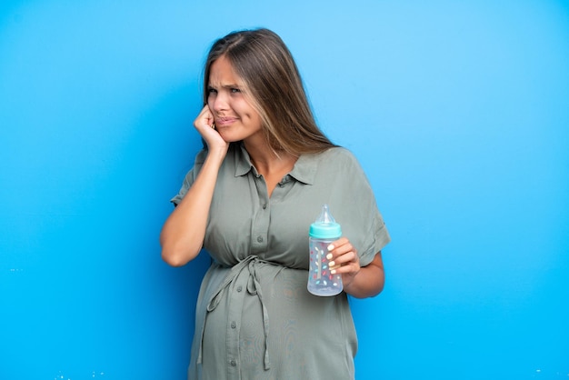 Femme enceinte sur fond bleu frustrée et couvrant les oreilles