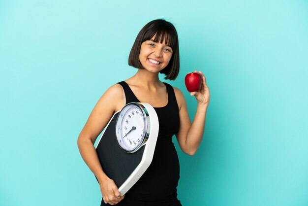 Femme enceinte sur fond isolé avec balance et avec une pomme