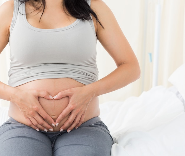 Femme enceinte en forme de coeur sur son ventre