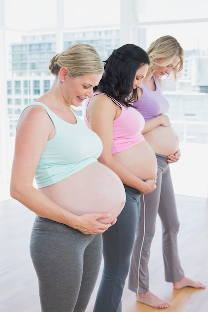 Femme enceinte gaie debout dans une ligne souriant à bosses