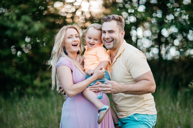 Une femme enceinte heureuse avec sa famille sur le terrain du parc.