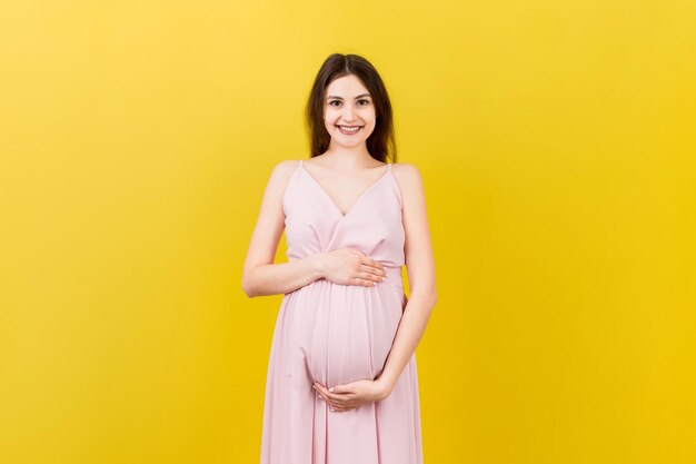 Une femme enceinte heureuse touchant son abdomen sur un fond coloré Une future mère s'attendant à un bébé Copier l'espace