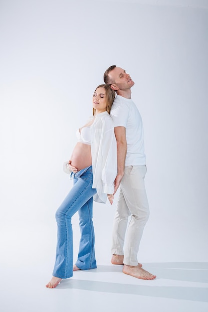 Une femme enceinte et un homme sont debout sur un fond blanc Belle jeune femme enceinte séduisante Concept d'accouchement de mariage familial Heureux couple enceinte