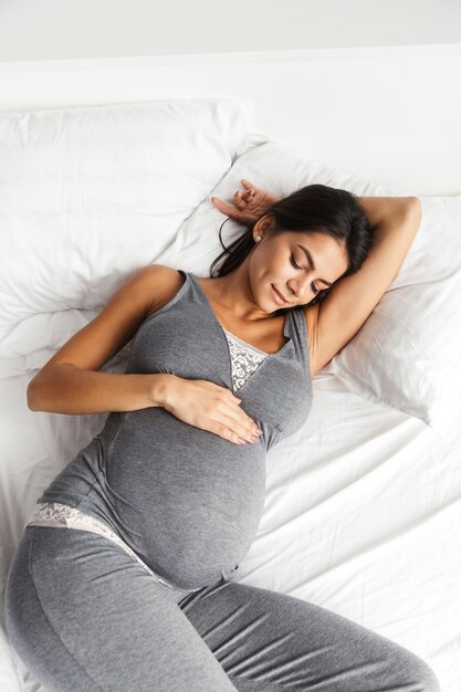 Femme enceinte à l'intérieur à la maison se trouve dans son lit.