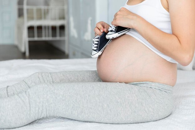 Une femme enceinte joue avec de petites chaussures.