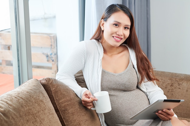 Femme enceinte lisant des nouvelles en ligne