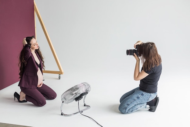 Photo femme enceinte lors d'une séance photo dans le processus de prise de vue en studio photographe avec modèle