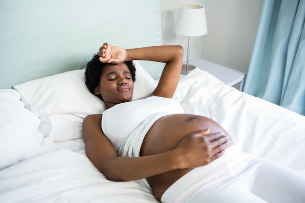 Femme enceinte avec mal de tête au lit