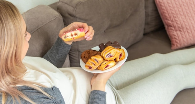 Une femme enceinte mange un beignet sucré Mise au point sélective