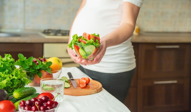 Une femme enceinte mange des légumes et des fruits