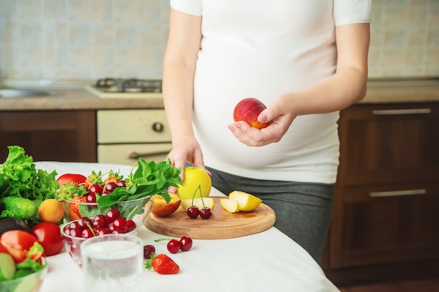 Une femme enceinte mange des légumes et des fruits