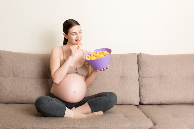 Femme enceinte, manger des chips dans un bol à la maison