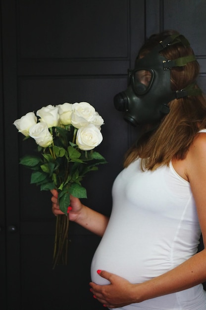 Photo une femme enceinte avec un masque debout près des roses blanches