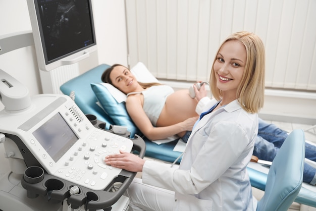 Femme enceinte et médecin à l'échographie, posant.