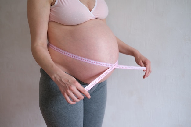 La femme enceinte mesure son ventre.