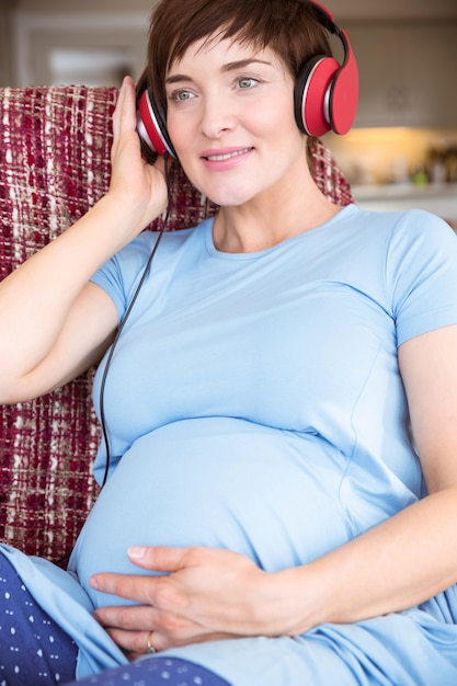 Photo femme enceinte, mettre des écouteurs sur la bosse