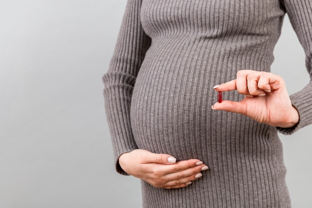 Femme enceinte montrant une pilule