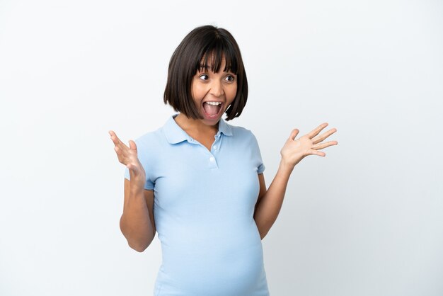 Femme enceinte sur un mur blanc isolé avec une expression faciale surprise