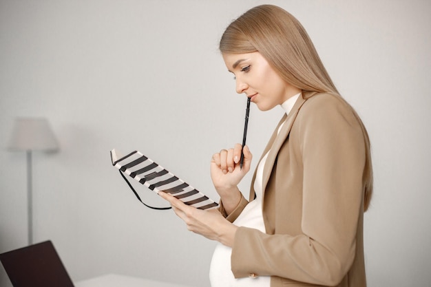 Femme enceinte avec ordinateur portable assis sur le bureau dans un bureau moderne