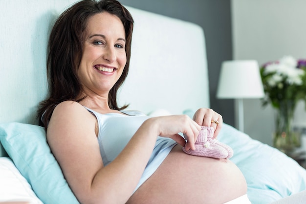 Femme enceinte avec des pantoufles tricotées sur le ventre dans la chambre à coucher