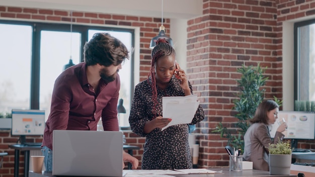 Femme enceinte parlant au téléphone pendant que l'homme utilise un ordinateur portable et analyse la stratégie marketing. Collègues travaillant ensemble sur la planification de projet au bureau. Gens d'affaires concevant l'analyse