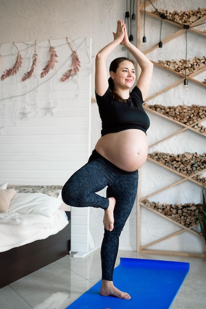 Femme enceinte pendant la formation de yoga et de sport à la maison