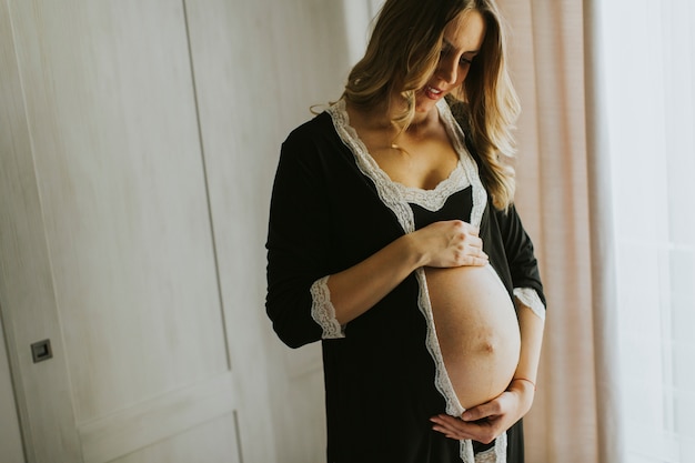 Femme enceinte portant de la lingerie et posant dans la chambre