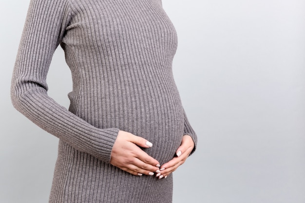 Femme enceinte portant une robe grise sur fond gris