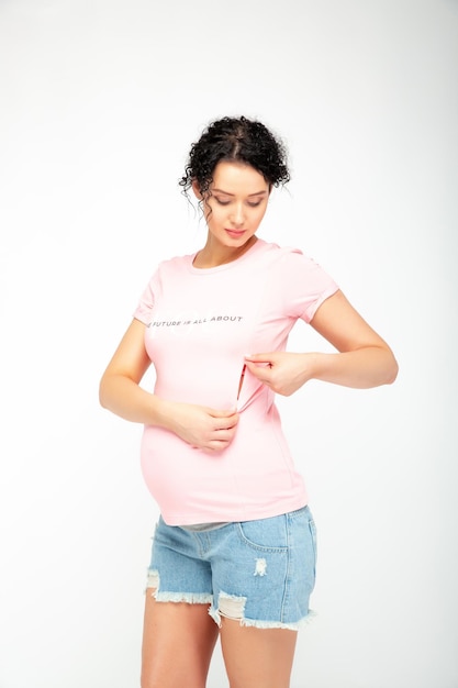 Une femme enceinte porte une chemise rose qui dit "qu'est-ce qu'une chemise" dessus