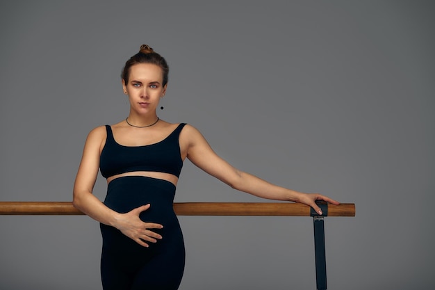 Femme enceinte posant près de barre dans un studio de ballet