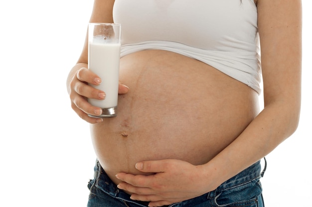 Femme enceinte posant avec un verre de lait isolé sur fond blanc