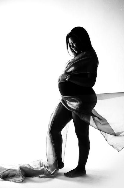 Une femme enceinte pose devant un fond blanc.