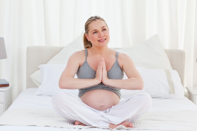 Femme enceinte pratiquant le yoga sur son lit