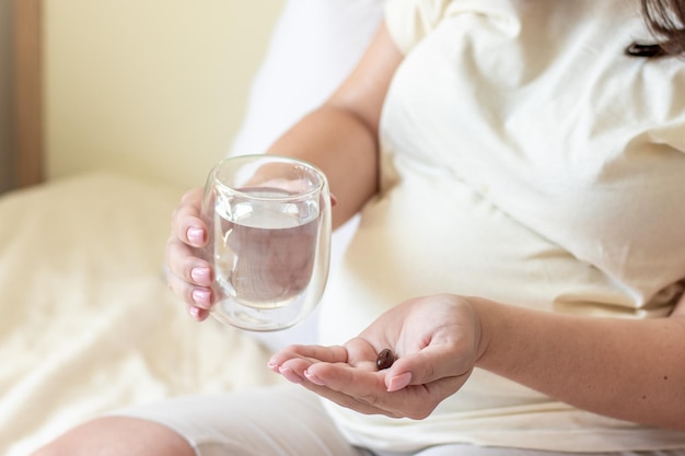 femme enceinte prend un complément alimentaire vitamines calcium vitamine c ou aspirine.main avec verre plein