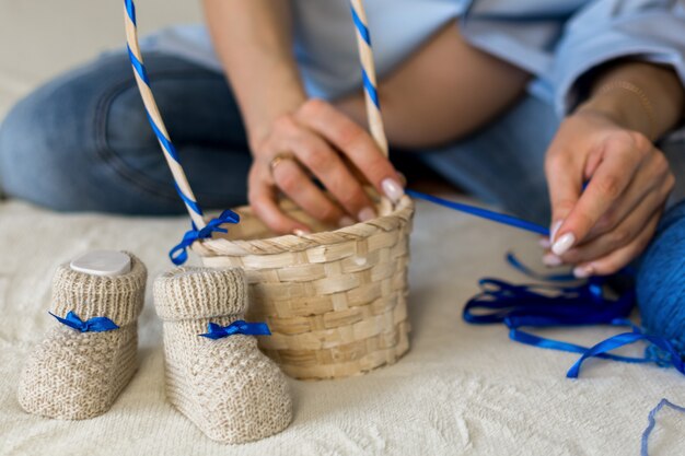 Une femme enceinte prépare un cadeau pour son enfant à naître met des chaussons pour bébé dans un panier en osier