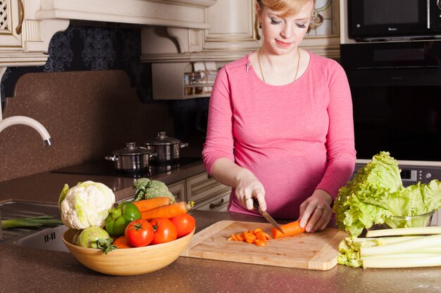 La femme enceinte prépare des plats dans la cuisine