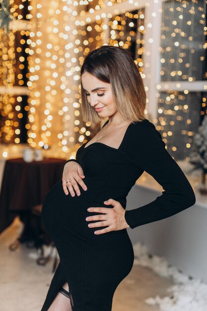 Femme enceinte près de l'arbre de Noël.