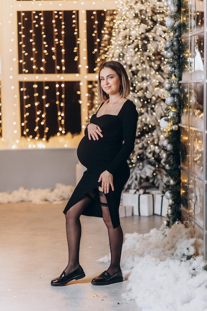 Femme enceinte près de l'arbre de Noël.