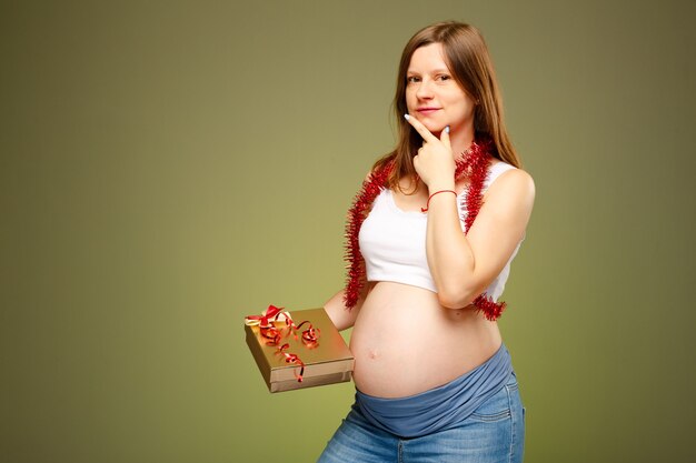 Femme enceinte avec le présent pensant quoi donner à un bébé ou à des parents à Noël