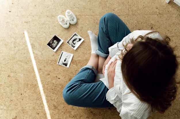 Une femme enceinte profitant de sa future maternité avec la première photo d'ultrason de son bébé. Vue supérieure avec espace libre.