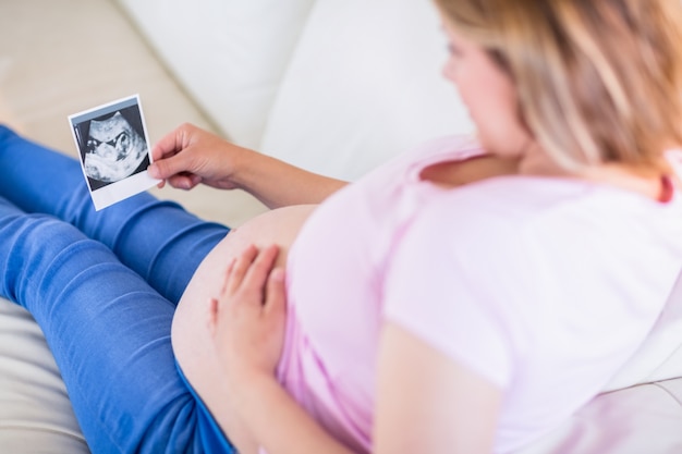 Femme enceinte en regardant les échographies et en touchant son ventre