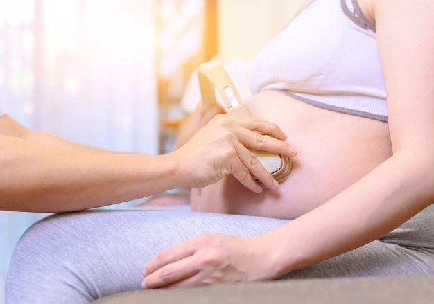 Une femme enceinte reste à la maison et donne son bébé pour une musique. Grossesse relaxante et saine.