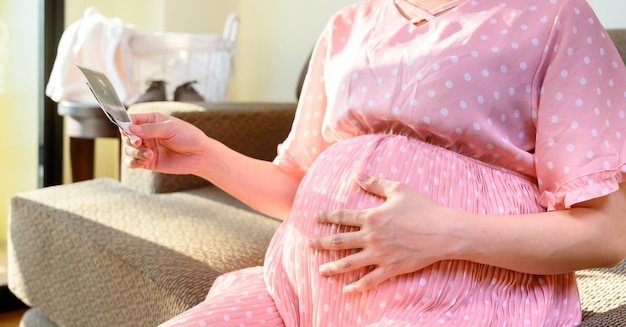 La femme enceinte reste seule à la maison. Grossesse à la recherche d'un nouveau bébé à venir.