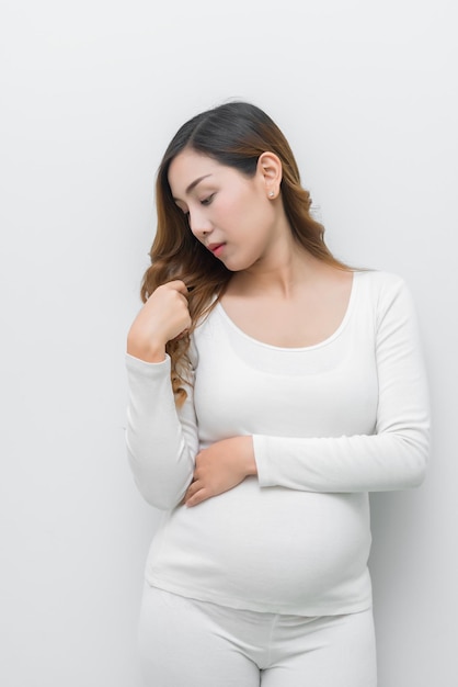 Une femme enceinte en robe blanche debout tenant son ventre