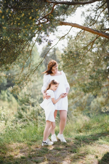 Femme enceinte et sa fille dans le parc au coucher du soleil Une famille heureuse