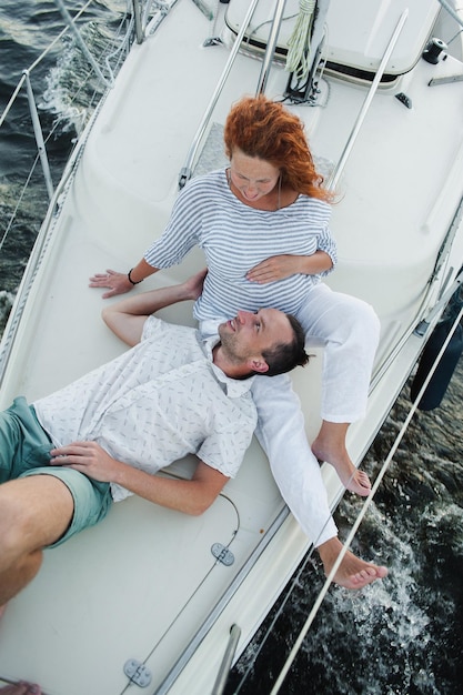 Une femme enceinte se caresse le ventre alors qu'elle était assise sur la proue du yacht